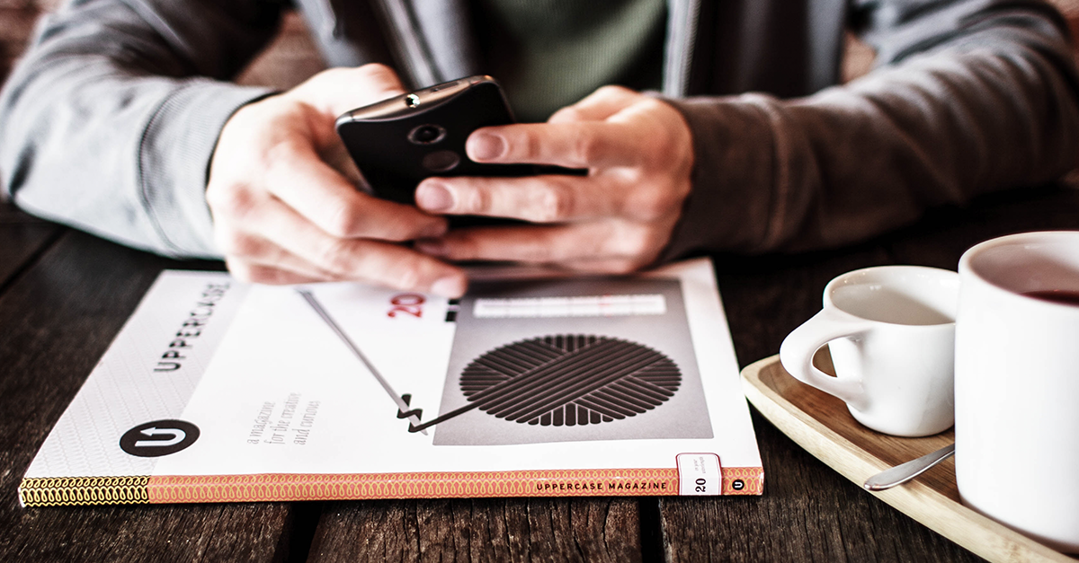 Person using mobile phone at table with a book